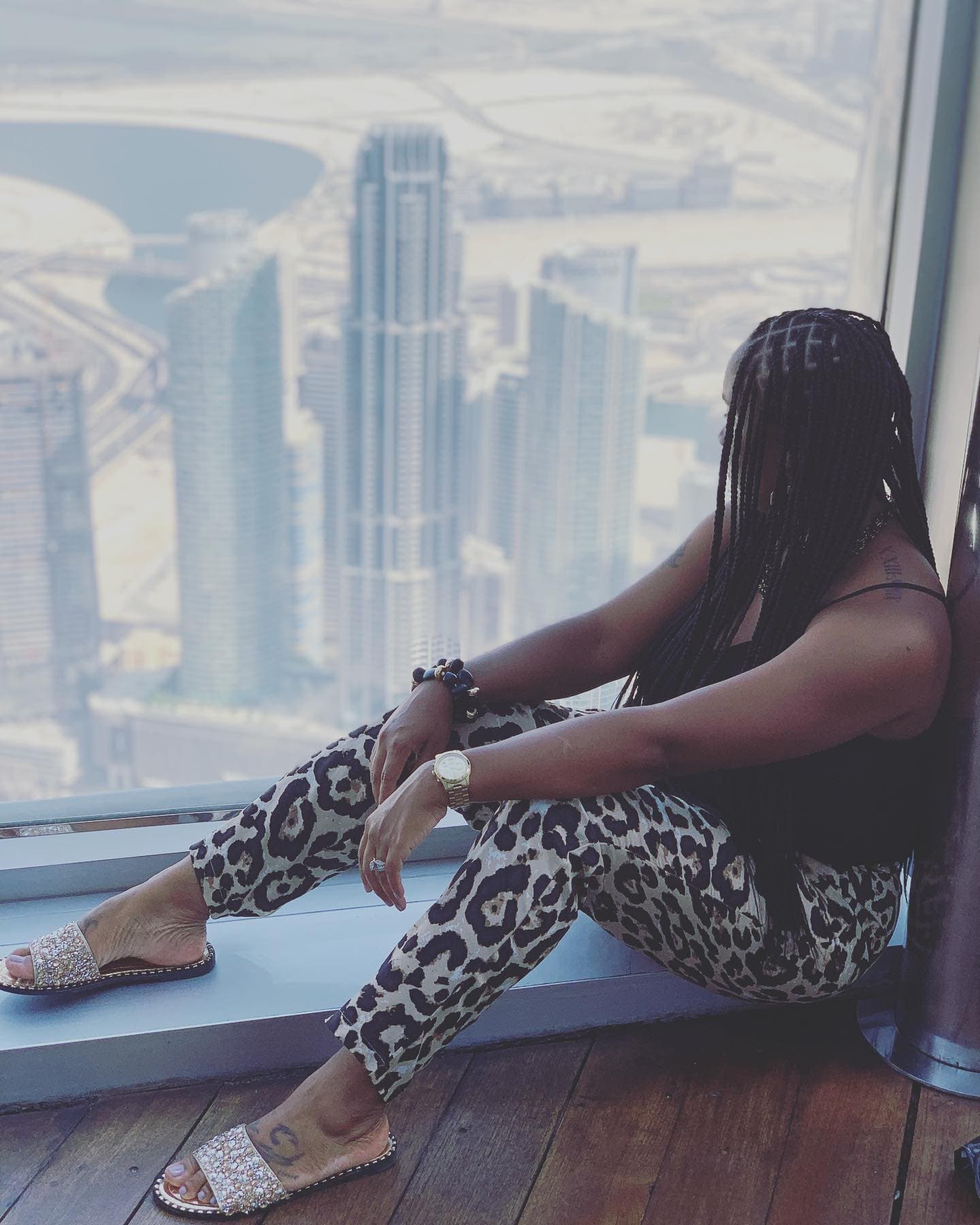 Neké Akua seated at a high-rise window, looking out over the Dubai skyline.