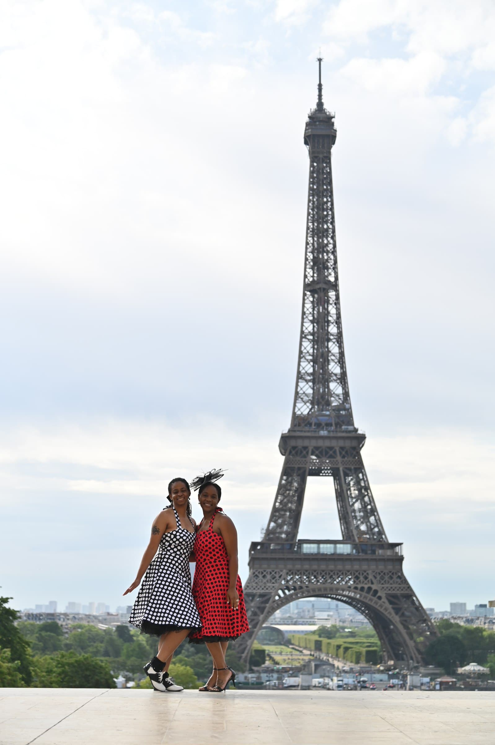 Neké Akua and a friend in polka-dot dresses walking in front of the Eiffel Tower in Paris.