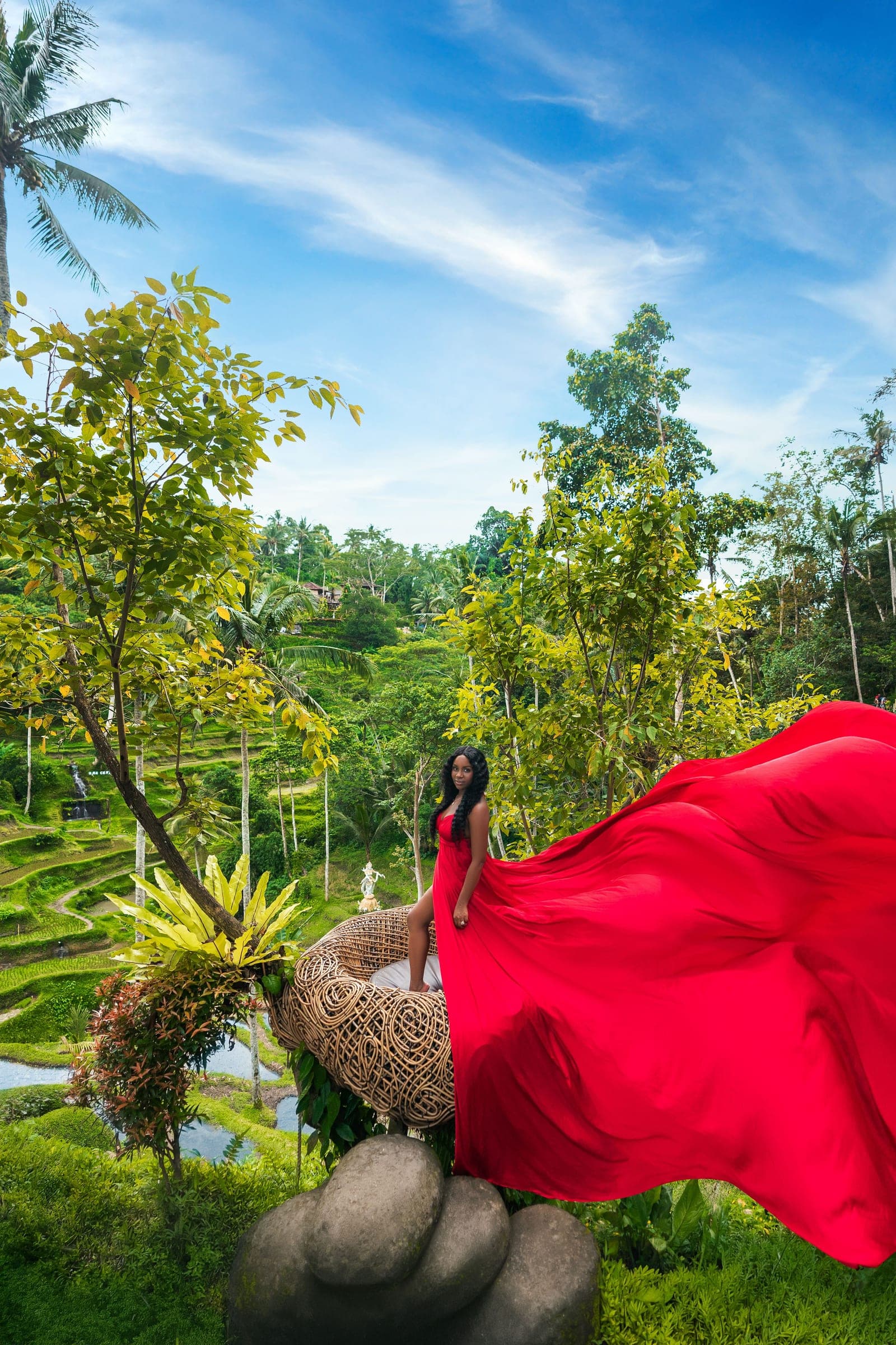 Neké Akua at a woven bamboo nest perched above the Tegallalang terraces, the train of her red gown flying out across the frame.